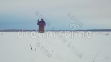 三个徒步旅行者带着徒步旅行杆，一个背包和雪鞋。 徒步旅行者小组冬季旅行愉快